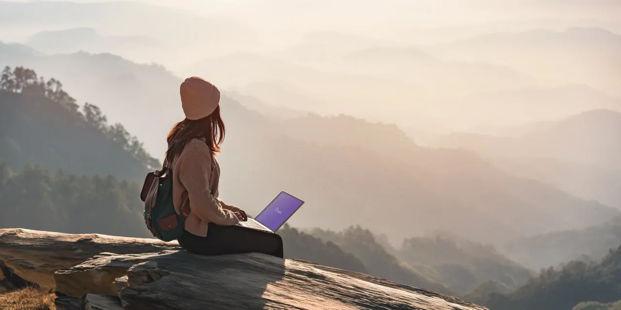 절벽에 앉아 산을 바라보며 노트북으로 일하는 여성